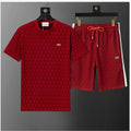 A red two-piece Lacoste set featuring a short-sleeve t-shirt and matching shorts, both with an allover geometric pattern. The t-shirt has a small crocodile logo on the left chest, and the shorts have a white stripe down the side with a small logo near the hem.